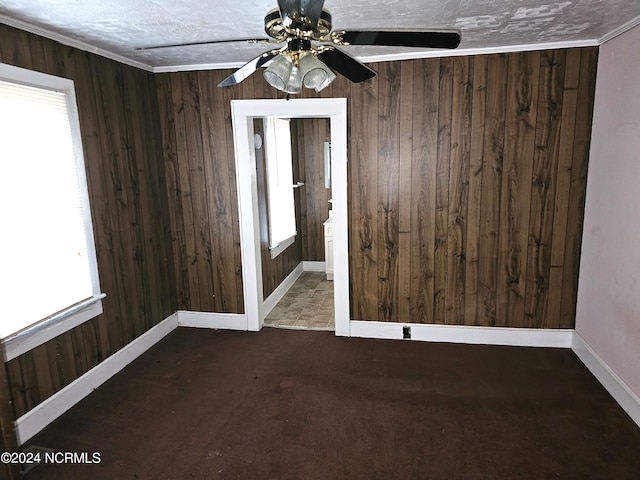 unfurnished room featuring wood walls, ceiling fan, and baseboards