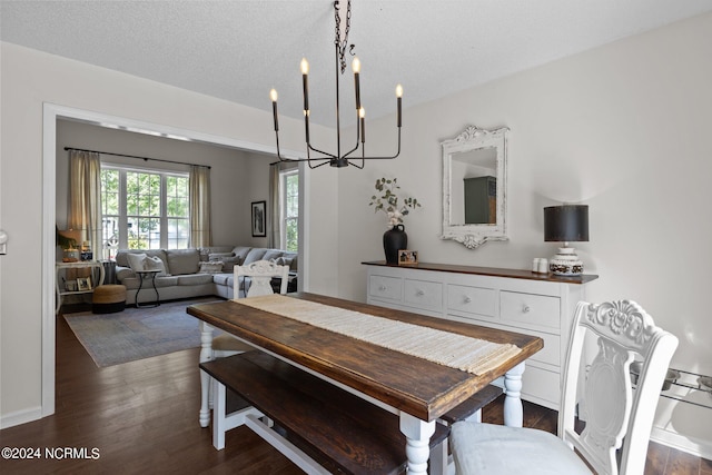 dining space with a textured ceiling, dark wood-type flooring, and an inviting chandelier