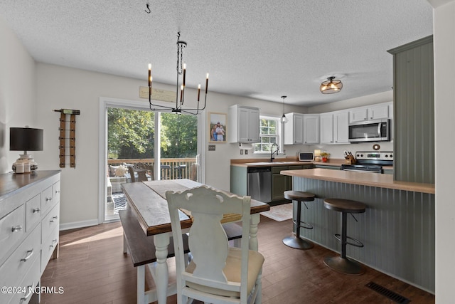 dining room with a textured ceiling, sink, dark hardwood / wood-style floors, and a notable chandelier