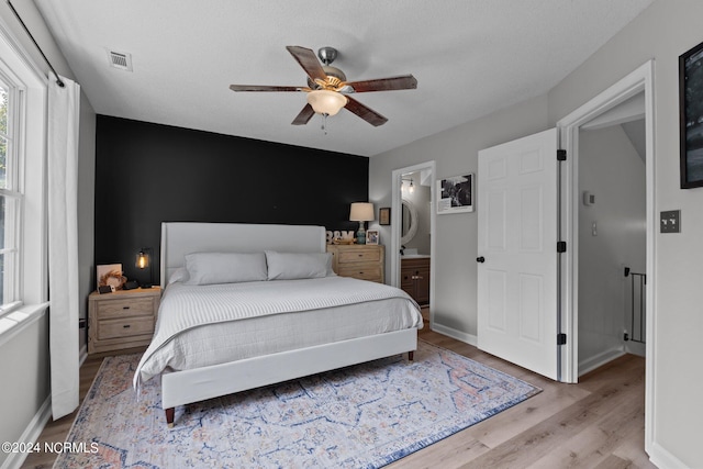 bedroom with ensuite bath, ceiling fan, and light hardwood / wood-style flooring