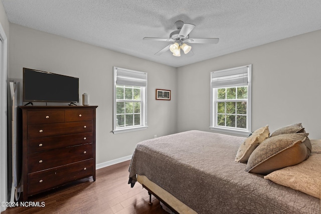 bedroom with hardwood / wood-style flooring, ceiling fan, and a textured ceiling