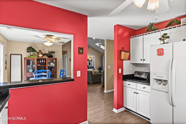 kitchen with ceiling fan, white fridge with ice dispenser, dark countertops, and white cabinetry