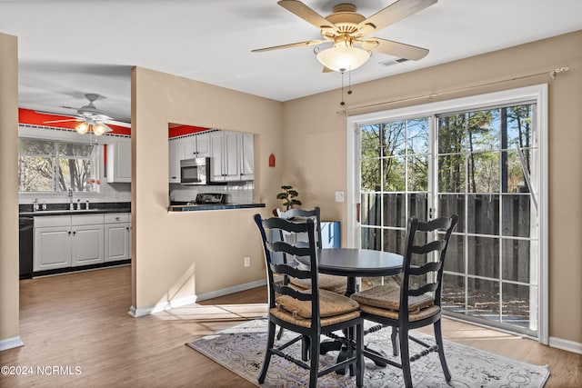 dining area featuring baseboards, visible vents, ceiling fan, and light wood finished floors