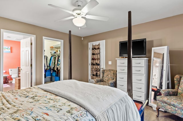 bedroom with ensuite bathroom, ceiling fan, wood finished floors, a spacious closet, and a closet