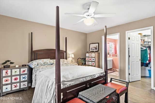 bedroom with a closet, a spacious closet, ceiling fan, ensuite bath, and wood finished floors