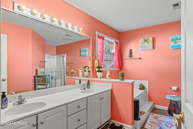 full bath with double vanity, a sink, visible vents, and a shower stall