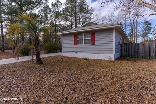 view of home's exterior featuring a shingled roof and fence