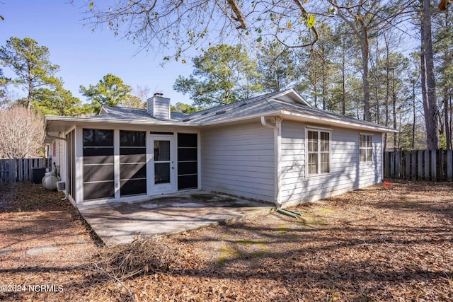 back of property with a sunroom, a chimney, fence, and a patio