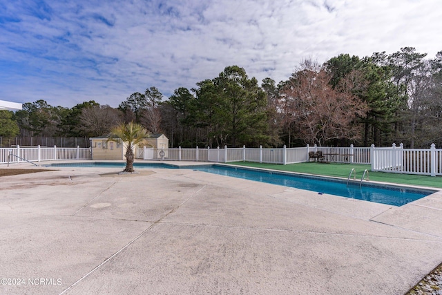 view of swimming pool with a patio area, fence, a fenced in pool, and an outbuilding