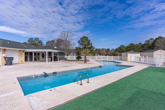 community pool featuring a patio area, a shed, fence, and an outdoor structure