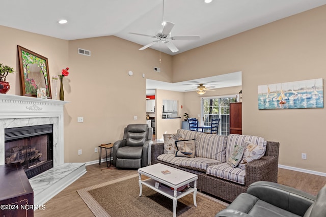 living room with lofted ceiling, visible vents, a premium fireplace, wood finished floors, and baseboards