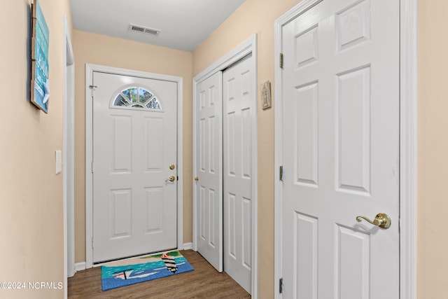 doorway to outside featuring baseboards, visible vents, and dark wood-type flooring