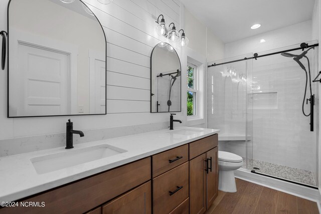 bathroom featuring wood-type flooring, vanity, a shower with shower door, and toilet