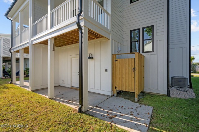 doorway to property with a lawn, a balcony, and central AC