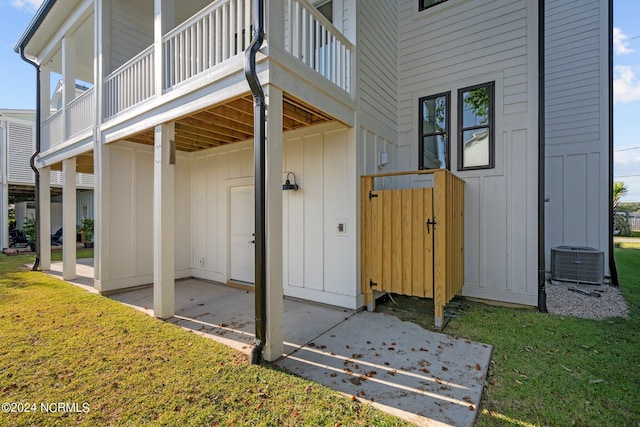 exterior space featuring board and batten siding, a lawn, a patio, and central air condition unit