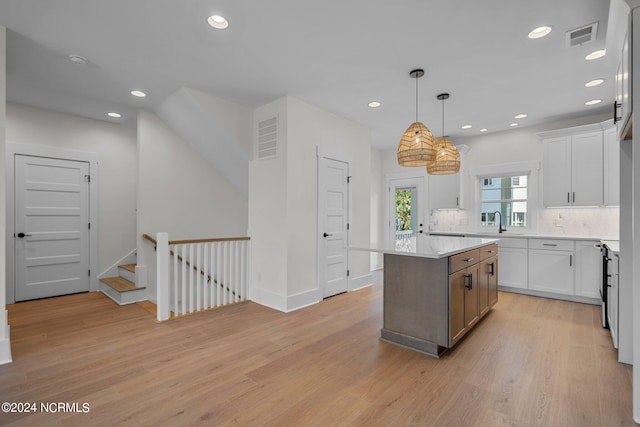 kitchen with pendant lighting, light hardwood / wood-style flooring, white cabinetry, and a kitchen island