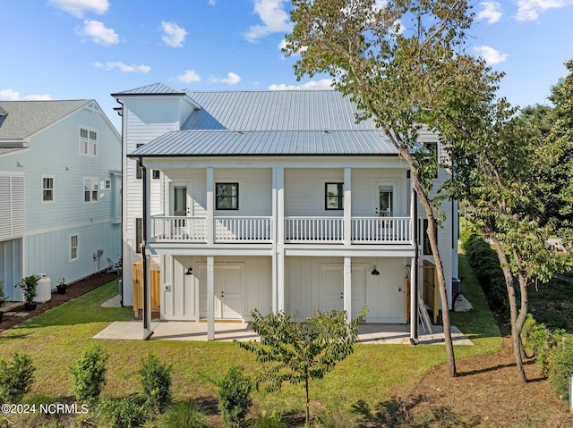 rear view of property featuring metal roof, a lawn, a patio area, and board and batten siding