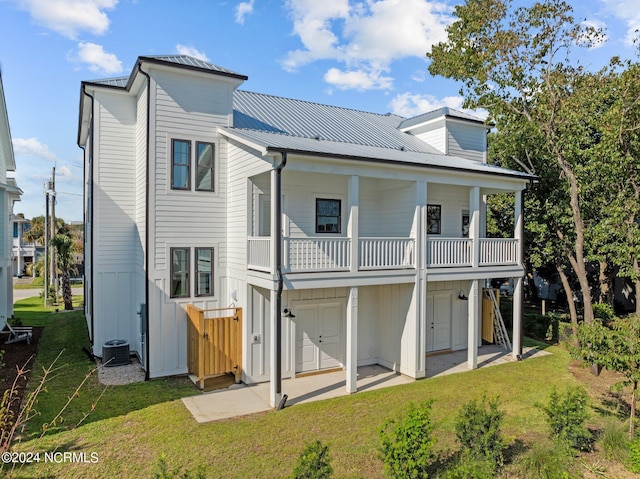 rear view of house featuring metal roof, a yard, central air condition unit, and a patio