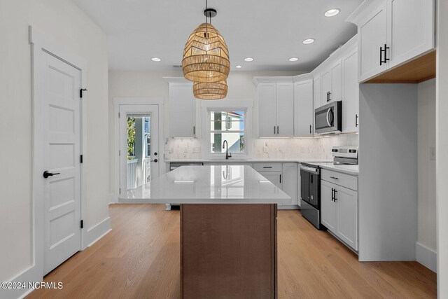 kitchen featuring appliances with stainless steel finishes, light hardwood / wood-style floors, white cabinetry, and a center island