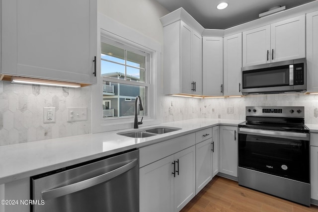 kitchen featuring appliances with stainless steel finishes, light countertops, a sink, and backsplash