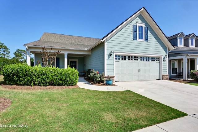 view of front of house with covered porch, a front yard, and a garage