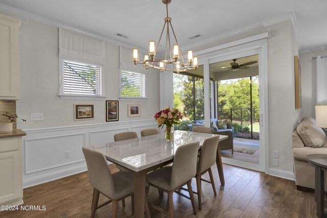 dining room featuring dark wood-type flooring, ornamental molding, and ceiling fan with notable chandelier