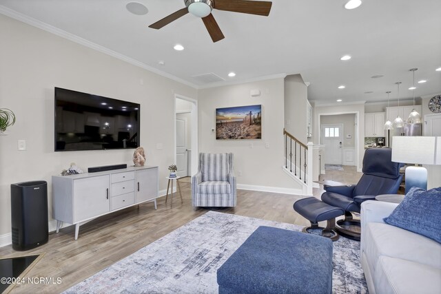 living room featuring crown molding, light hardwood / wood-style flooring, and ceiling fan