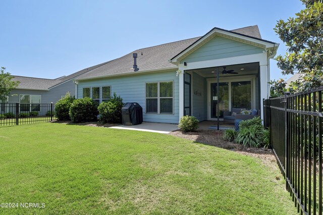 rear view of property with ceiling fan, a lawn, and a patio