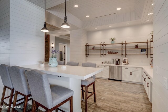 kitchen with white cabinets, light hardwood / wood-style flooring, decorative light fixtures, kitchen peninsula, and a kitchen breakfast bar