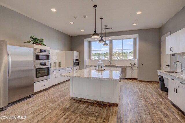 kitchen with light hardwood / wood-style flooring, stainless steel appliances, sink, and white cabinets