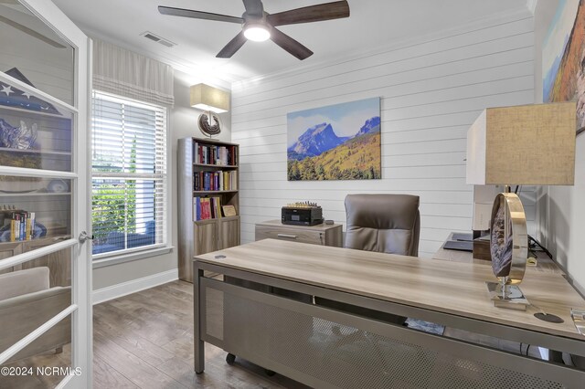 office area with ceiling fan, dark hardwood / wood-style floors, crown molding, and wooden walls