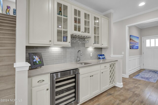 interior space featuring wine cooler, sink, light wood-type flooring, and white cabinetry