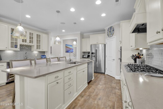 kitchen with a breakfast bar area, stainless steel appliances, an island with sink, and hanging light fixtures