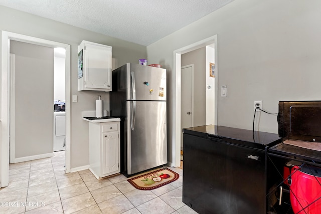 kitchen with stainless steel fridge, white cabinetry, a textured ceiling, light tile patterned floors, and washer / clothes dryer