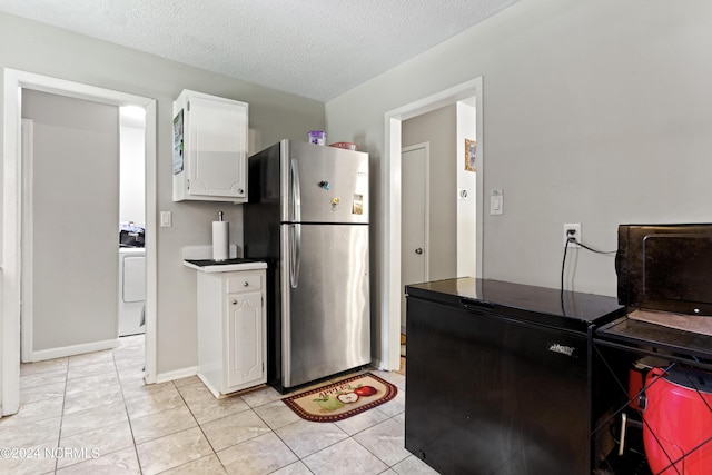 kitchen with refrigerator, freestanding refrigerator, white cabinets, a textured ceiling, and washer / dryer