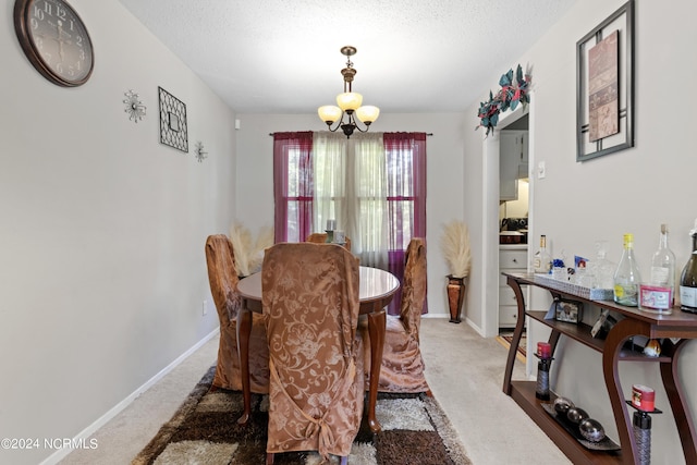 dining room featuring carpet flooring, a textured ceiling, baseboards, and an inviting chandelier