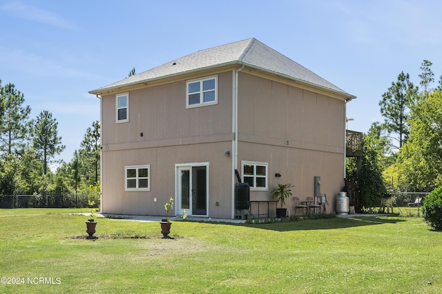 back of property with a lawn and fence