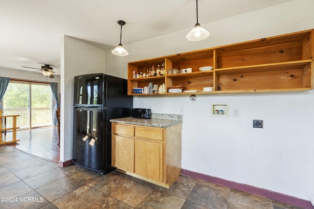 kitchen with light stone counters, hanging light fixtures, freestanding refrigerator, ceiling fan, and baseboards