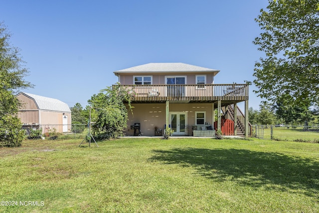 rear view of house featuring a lawn, a fenced backyard, a deck, french doors, and stucco siding