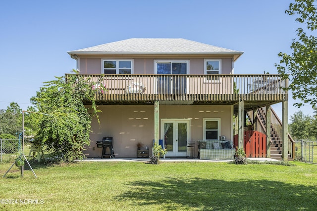 rear view of house featuring french doors, stucco siding, a lawn, stairway, and fence