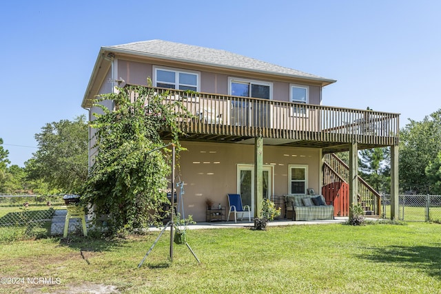 rear view of house featuring stucco siding, a lawn, a wooden deck, and fence