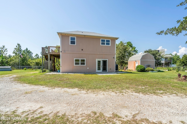 rear view of property featuring an outbuilding, a yard, a deck, and french doors