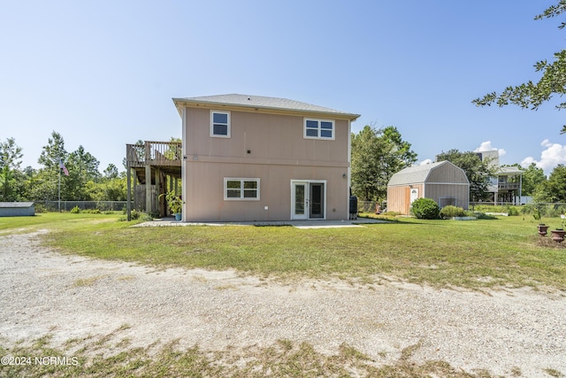 back of property featuring an outbuilding, french doors, a lawn, fence, and a deck