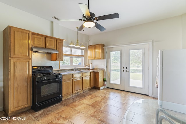 kitchen featuring black gas range, freestanding refrigerator, french doors, under cabinet range hood, and a sink