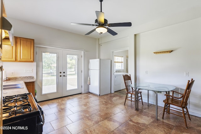 kitchen featuring french doors, washer and clothes dryer, black gas range, freestanding refrigerator, and a sink