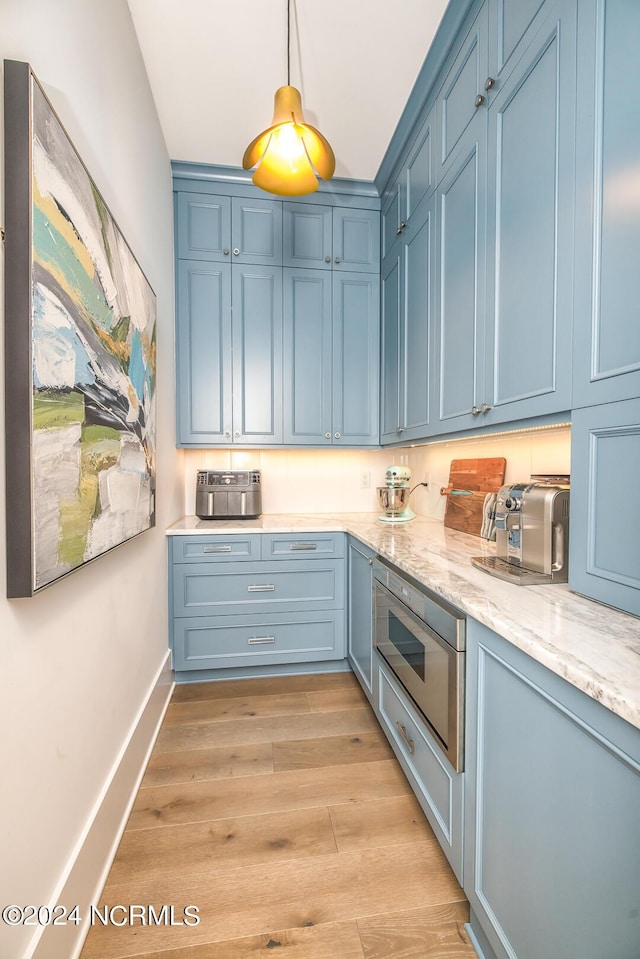 6404 Westport Dr, Wilmington, NC 28409 - kitchen featuring blue cabinetry, light wood-style floors, stainless steel microwave, baseboards, and decorative light fixtures