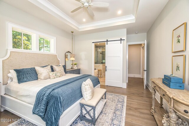 6404 Westport Dr, Wilmington, NC 28409 - bedroom with a barn door, a raised ceiling, wood finished floors, ensuite bath, and baseboards