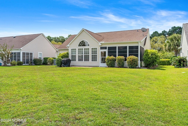 rear view of house featuring a sunroom and a lawn