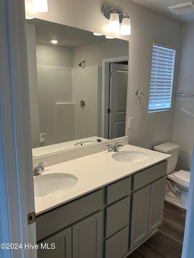 bathroom with a shower, hardwood / wood-style floors, vanity, and toilet