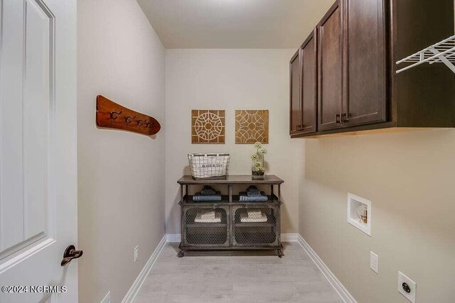 washroom with washer hookup, light hardwood / wood-style flooring, cabinets, and hookup for an electric dryer